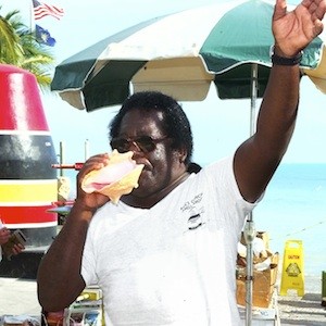 Bishop Albert Kee welcomed visitors to Key West's Southernmost Point marker, acting as a smiling ambassador for the island while selling fluted, pink-lined conch shells beside the iconic landmark. 